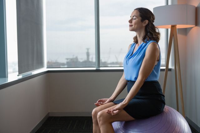 Executive meditating on fitness ball in office