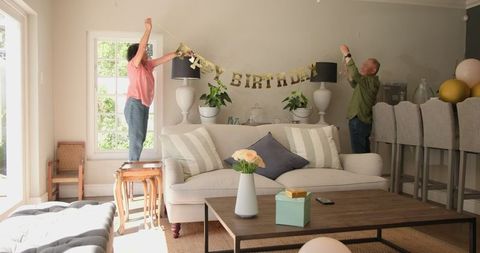 Seniors Hanging Birthday Banner in Cozy Living Room