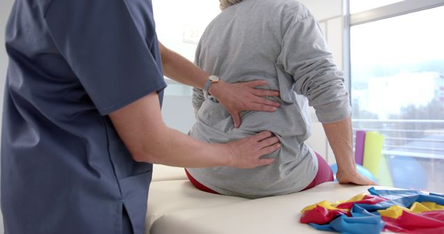 An elderly patient is receiving treatment for lower back pain from a physical therapist. This image is ideal for illustrating concepts related to healthcare for the elderly, physiotherapy practices, chronic pain management, and rehabilitation services. Can be used in medical and wellness articles, physical therapy websites, educational materials on senior healthcare, and brochures for rehabilitation centers.
