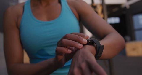 Athletic woman checking fitness app on smartwatch at gym