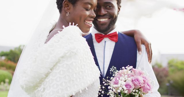 Happy african american couple embracing and smiling during wedding. Wedding day, friendship, inclusivity and lifestyle concept.