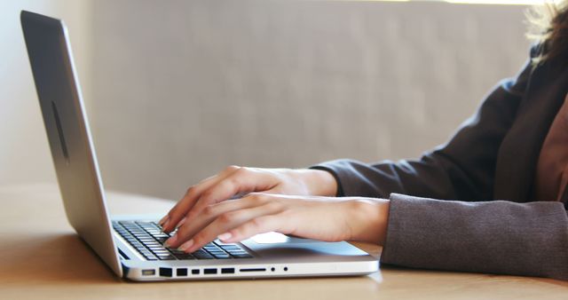 This image depicts a businesswoman in office attire typing on a laptop at her desk. The scene suggests a professional environment, ideal for use in materials related to business, technology, careers, professional development, and office-related topics.