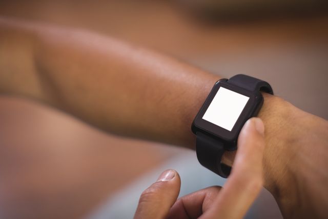 Close-up of man using smart watch in living room at home