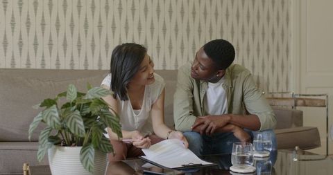 Multicultural couple planning wedding at home with documents