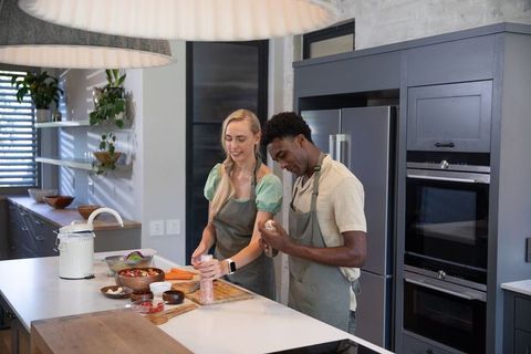 Couple Seasoning Vegetables in Modern Kitchen Interior