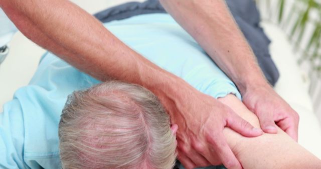 Senior man receiving shoulder massage by physiotherapist. Physiotherapist massaging the patient's shoulder to provide pain relief and improve mobility. Ideal for illustrating healthcare, physical therapy, senior care, rehabilitation processes, and wellness services.