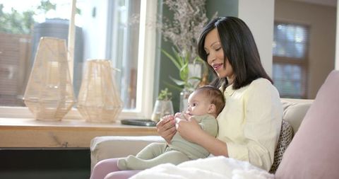 Mother cozy with newborn on sofa in light-filled living space
