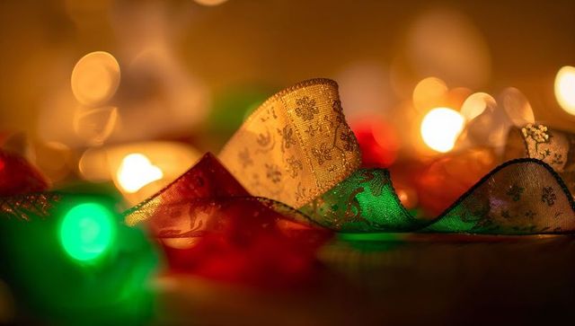 Shimmering gold red and green holiday ribbons sparkling with warm bokeh lights