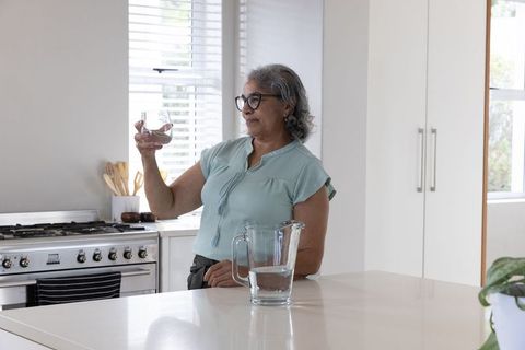 Senior Woman Enjoying Hydration in Modern Kitchen