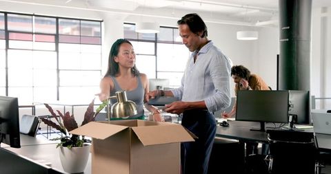 Colleagues unpacking office box in collaborative workspace
