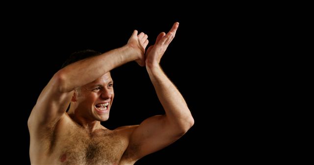 This image depicts a cheerful and shirtless man clapping his hands enthusiastically against a black background. His expressive demeanor conveys excitement and positivity. This image can be used in sports promotions, fitness advertisements, motivational materials, and other contexts where expressions of triumph and enthusiasm are needed.