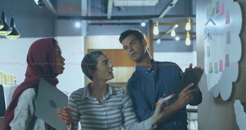 Diverse Business Team Analyzing Financial Data on Whiteboard in Modern Office