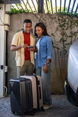 Couple Checking Travel Plans Next to Luggage and Minivan