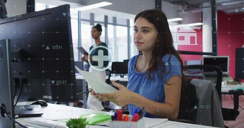 Businesswoman Analyzing Financial Reports on Computer in Modern Office