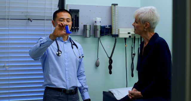 Young Asian male doctor and senior patient discussing over asthma inhaler at clinic. Caucasian senior patient looking at asthma inhaler 4k