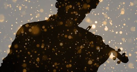 Silhouette Violinist Playing Amid Moving Light Patterns