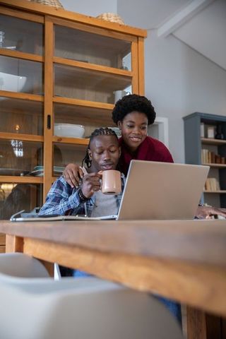 African American Couple Enjoying Coffee and Work at Home Dining Table