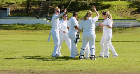 Diverse Female Cricket Team Celebrating Victory on Grass Pitch
