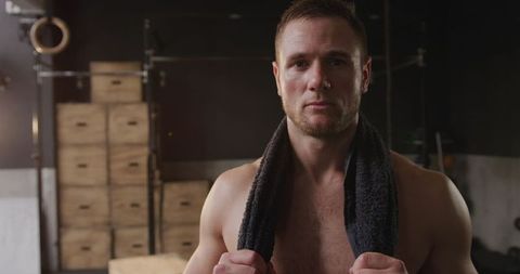 Athletic Caucasian Man Resting at Gym After Intense Workout Holding Towel