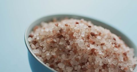 Close-up of himalayan salt crystals in bowl on blue background