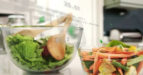 Serving fresh garden salad in glass bowls with wooden spoon and julienned carrot mix