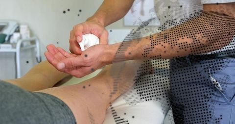 Therapist applying moisturizer to patient's lower leg during rehabilitation session