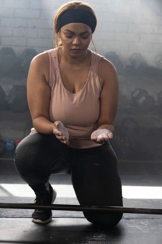 Focused african american woman preparing with chalk at gym before heavy lift