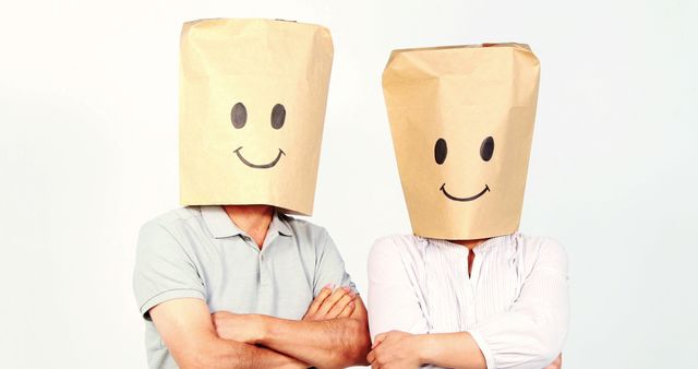 Two adults with paper bags over their heads stand with arms crossed, featuring drawn-on smiley faces, with copy space. Their hidden identities and the smiley faces create a humorous and mysterious atmosphere.
