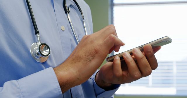 Mid section of doctor using mobile phone at the hospital
