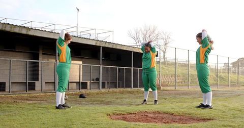 Female softball players stretching on field before game