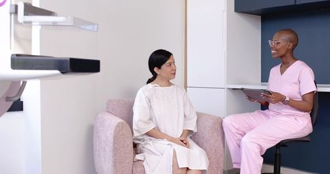 Patient Consulting Nurse in Pink Scrubs During Outpatient Exam Room Visit and Assessment
