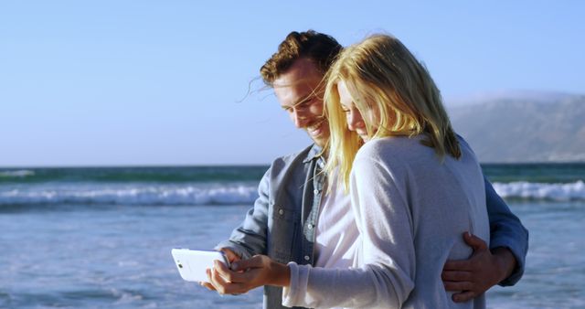 Happy couple taking selfie on sandy beach during a sunny day. Great for promoting vacation destinations, travel agencies, romantic getaways, summer activities or social media content related to love and relationships.