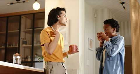 Diverse couple chatting over coffee at kitchen island with french press and cozy interiors
