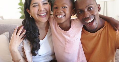 Smiling family embracing on sofa enjoying playful moment, togetherness and home warmth