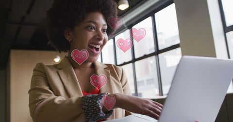 Excited woman using laptop with floating heart icons