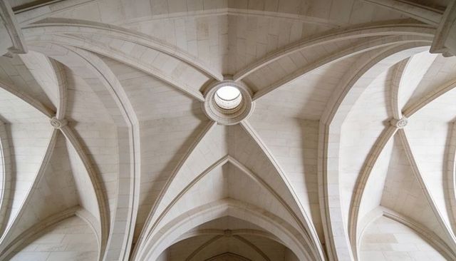 Symmetrical gothic limestone ribbed vault ceiling with central oculus and pointed arches