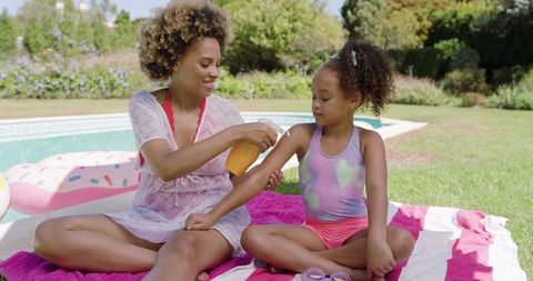 Mother and Daughter Bonding with Sunscreen by the Poolside