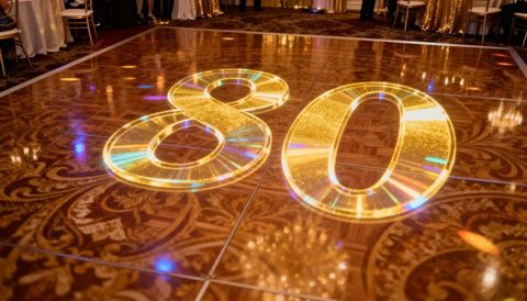 Glamorous 80th birthday number projecting on polished ballroom dance floor