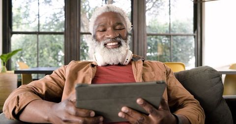 Senior Man Enjoying Tablet with Headphones in Cozy Living Room