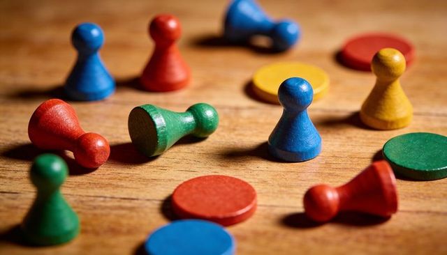 Scattered colorful wooden pawns and tokens creating warm tabletop boardgame composition