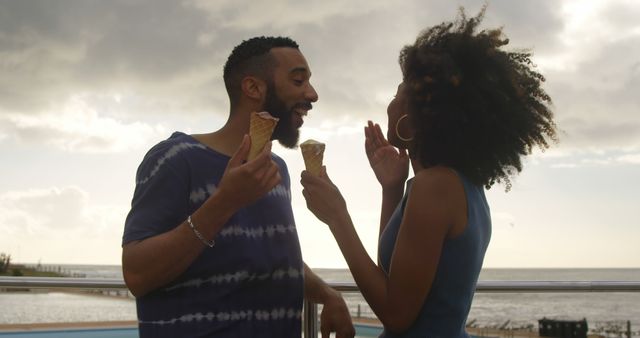 Happy couple enjoying ice cream by the beach at sunset - Download Free Stock Images Pikwizard.com