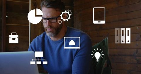 Bearded man working on laptop in rustic wood office with cloud and analytics icons