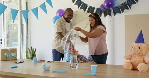 Diverse couple celebrating birthday at home with party decorations