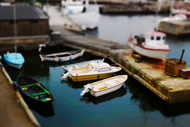 Multiple small colorful boats are docked at a marina with calm water. The scene is tranquil and captures maritime life beautifully. Ideal for use in travel brochures, magazines, websites about fishing and boating, and promotional materials for marina-related activities.