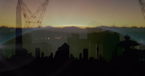 Silhouetted urban skyline at dusk with mountains and power lines