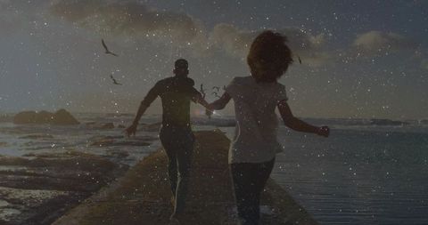 Couple Running on Pier at Ocean Sunset with Flying Seagulls