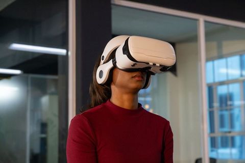 Indian woman wearing VR headset exploring immersive virtual reality at modern glass office