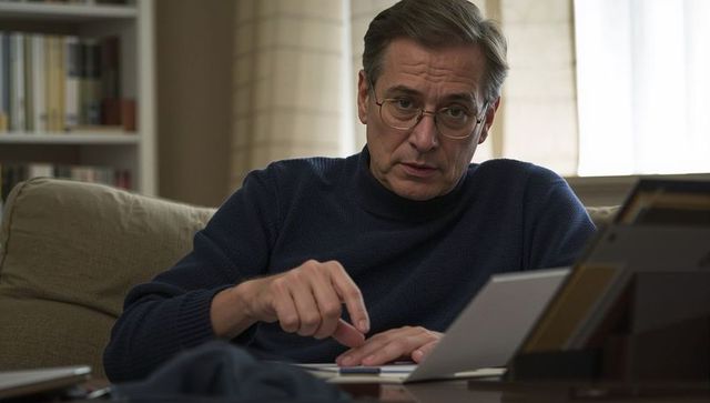 Mature man pointing at tablet while reviewing documents on living room coffee table