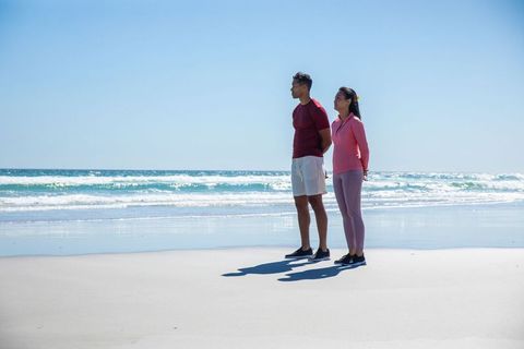 Couple Standing on Sunny Beach in Athletic Clothes