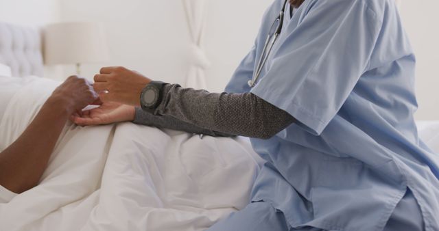 Midsection of senior african american woman lying in bed and holding hands with female doctor - Download Free Stock Photos Pikwizard.com